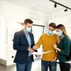 Real,Estate,Agent,And,Young,Couple,Examining,Blueprints,On,A