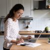 Female,Standing,In,Home,Kitchen,Doing,Accounting,Work,From,Home