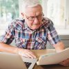 Worried,Senior,Man,Looking,At,A,Document,While,Using,Laptop