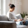 Smiling,Indian,Millennial,Girl,Sit,Relax,On,Couch,Using,Modern