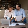 Happy,Couple,Of,Tenants,,Homeowners,Doing,Domestic,Paperwork,,Reading,Paper