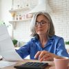 Homeowner’s Insurance Premiums Skyrocket: Forcing Homeowners to Consider Moving Senior,Mature,Business,Woman,Holding,Paper,Bill,Using,Calculator,,Old